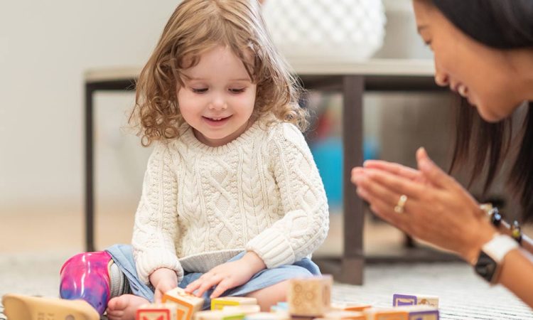 a child smiling while playing with blocks