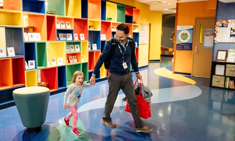 A young girl leaving school with her father happily