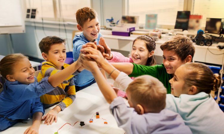 young kids in class joining hands together